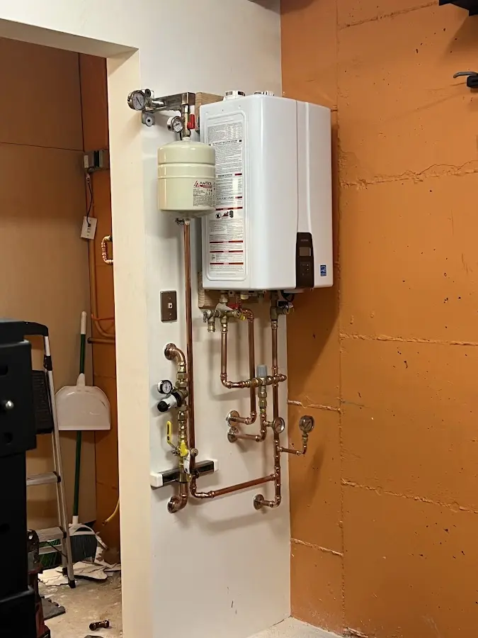 Plumbing technician inspecting water heater connections in St. Cloud